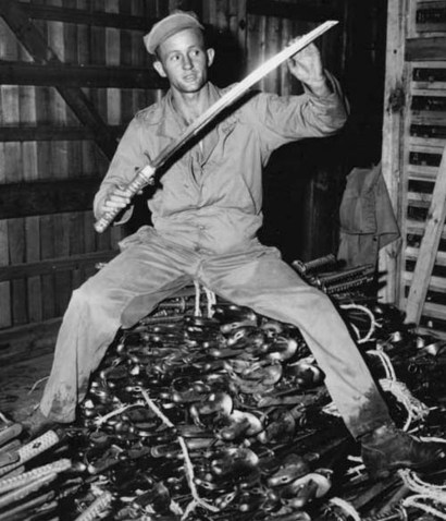 A US serviceman poses with a sword surrendered during the occupancy of Japan post-WW II. Many of these swords would be brought back to the US by soldiers as war trophies.
